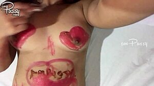נערה מתבגרת מציירת על גופה האסייתי החשוף עם שפתון בסרטון תוצרת בית
